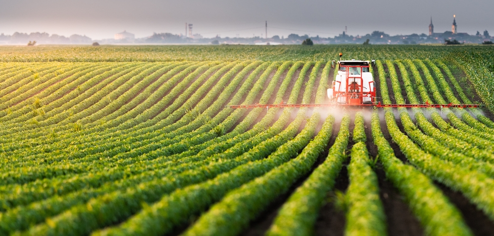 Tractor spraying crops in a field - article about natural-gas based Shell GTL’s uses vs. crude oil sourced paraffinic agricultural spray oil