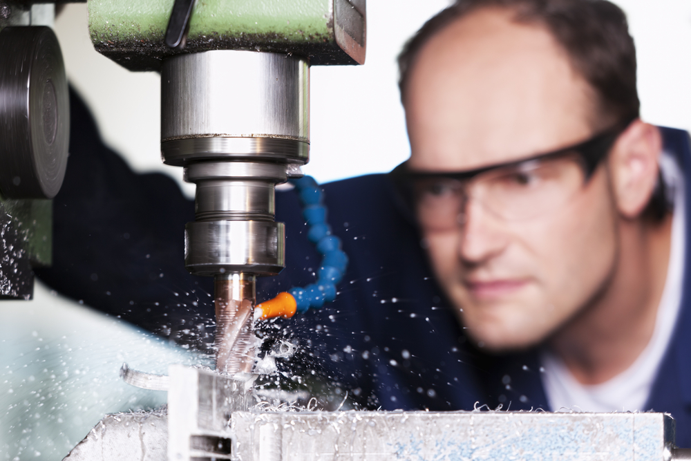 Close-up of a worker in a workshop with safety glasses working with a production aid fluid for a milling machine