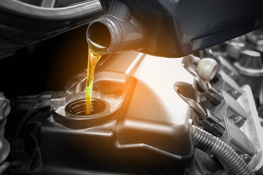 Pouring amber-colored oil into a car engine - article about base oil suppliers
