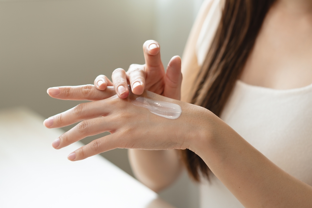 woman applying lotion to her hand - article about medical-grade oil suppliers