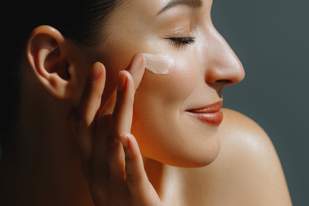 young woman applying moisturizer on her face - article about oils used in cosmetics